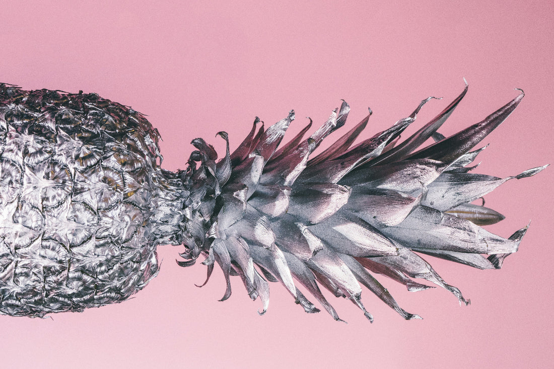 silver coated pineapple in front of pinky wall